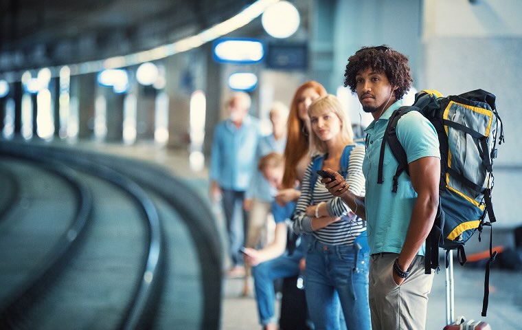Young woman assisting female friend while buying hat in market during vacation